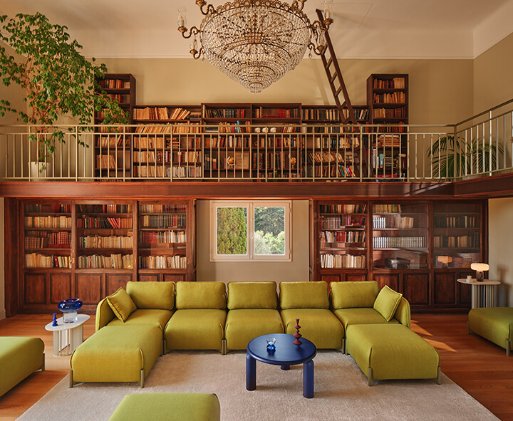 A modern coworking space furnished with office furniture, bookcases and colourful poufs.