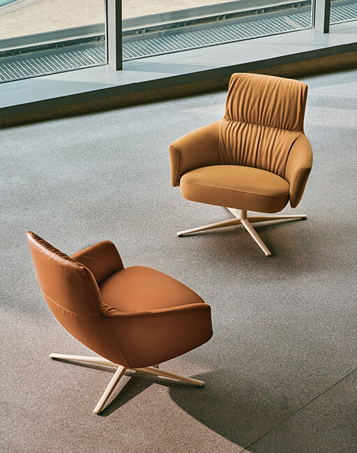 Two upholstered lounge chairs in shades of brown on swivel metal bases