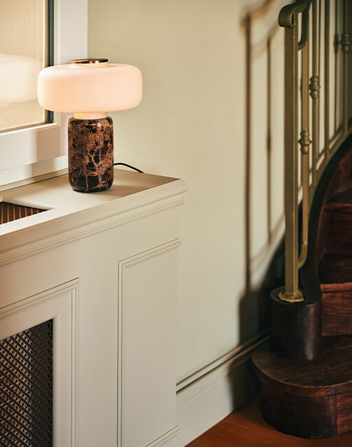 Table lamp with a white lampshade and marble base placed in front of a window