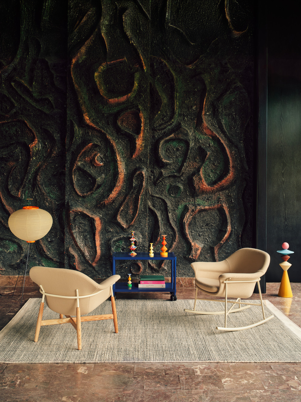 Two beige Ismo armchairs set in front of a brutalist mosaic