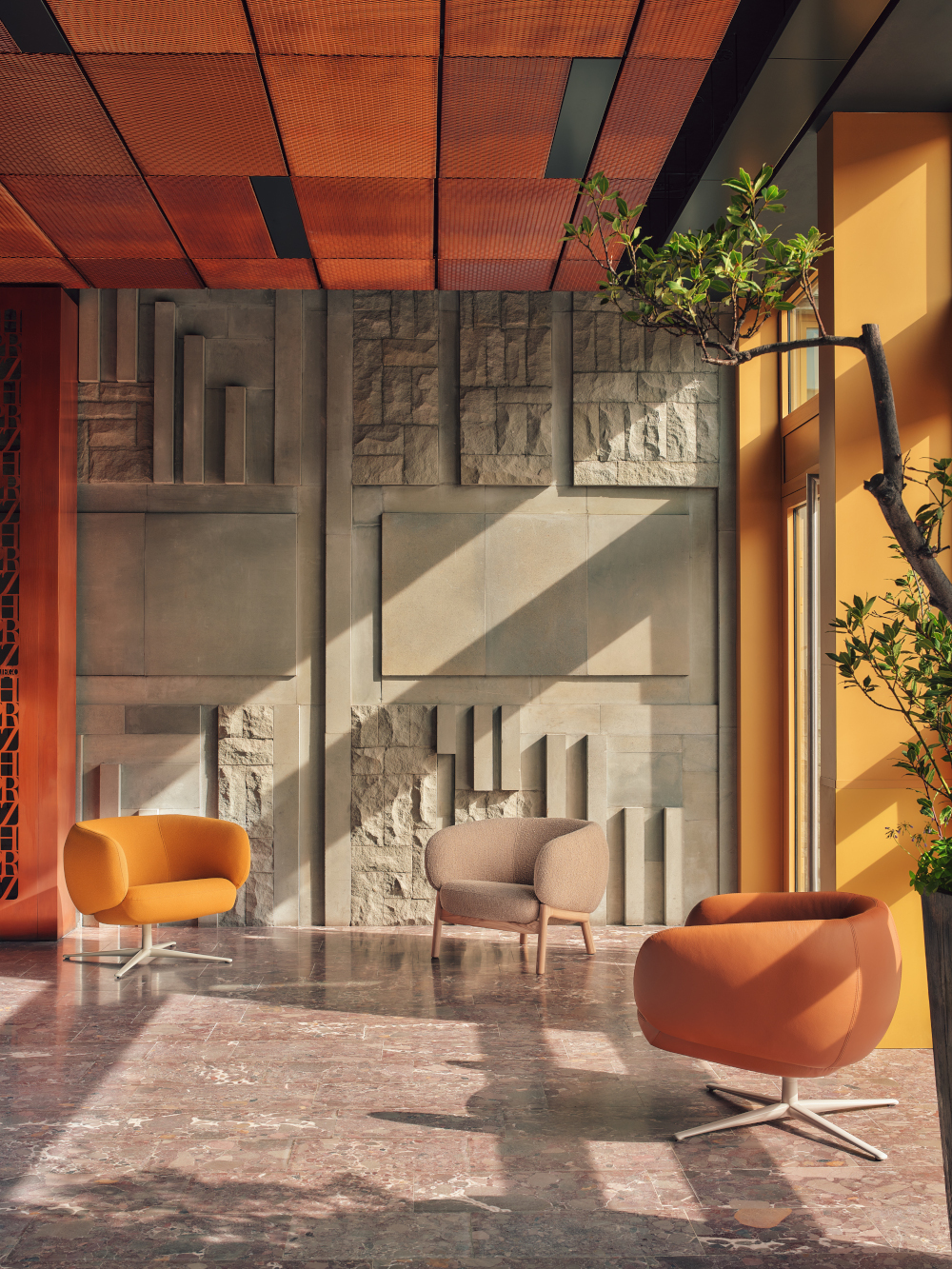Beige, yellow and brown Grand Grace armchairs in a sunny space by a concrete mosaic