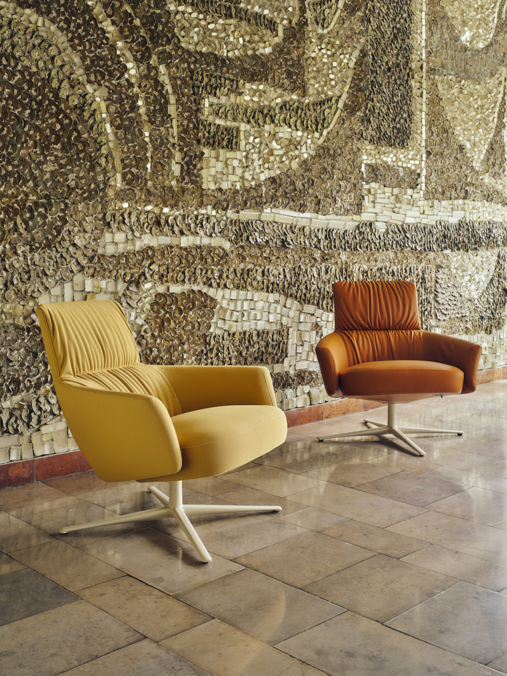 Beige and brown Toro armchairs set in front of a wall with stone mosaic