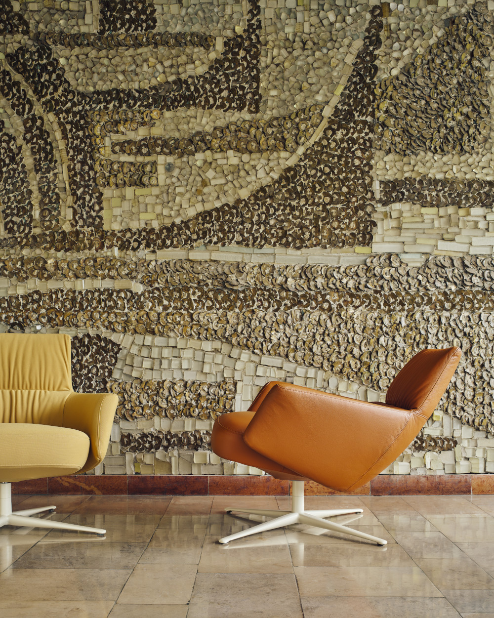 A titled brown leather Toro armchair in front of a stone mosaic