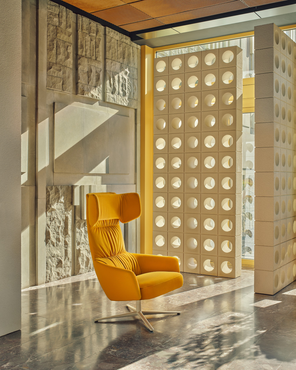 Yellow Toro armchair with wide headrest set against an architectural background