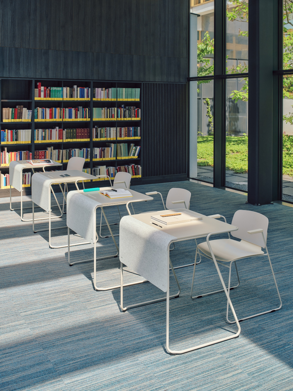 Small grey desks and conference chairs arranged in a library space