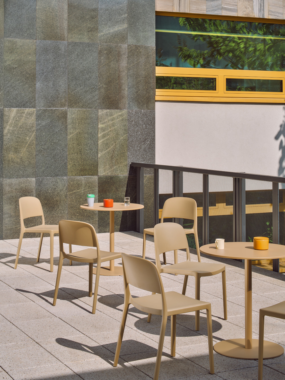 Beige plastic Blendy chairs and round Bolt tables on a sunny terrace
