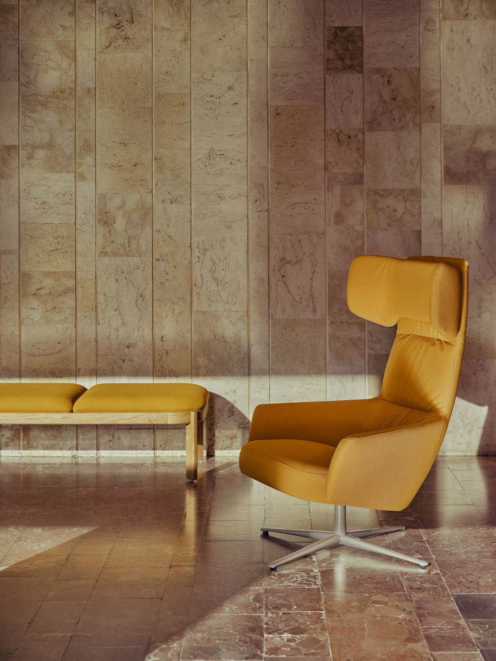Yellow armchair with wide headrest set against a stone wall