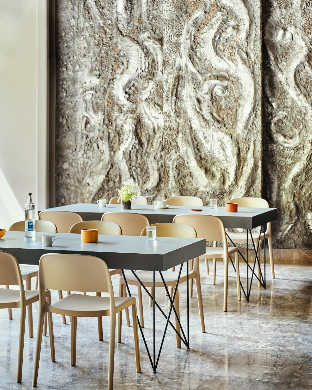 A canteen arranged with beige plastic chairs and grey modern dining tables