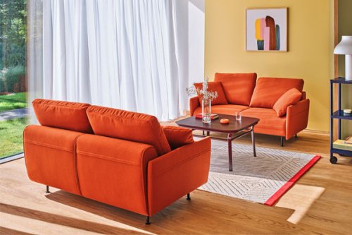 Light grey corner sofa with soft back cushions and slender metal legs